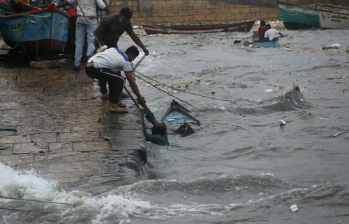 People rescue a man whose boat capsized in heavy waves on the Arabian Sea coast in Veraval, Gujarat, India. (AP Photo/Ajit Solanki)