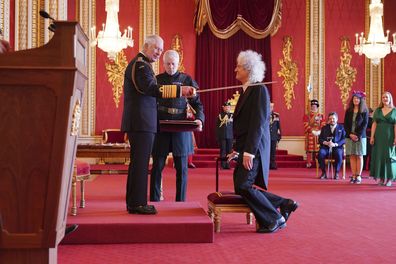 Brian May receiving his knighthood from King Charles at Buckingham Palace