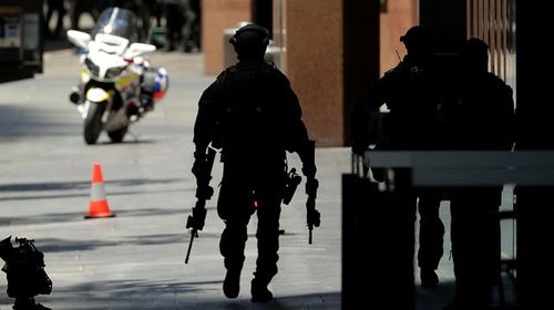 An armed policeman on Philip St walking towards Martin Place. (Getty)