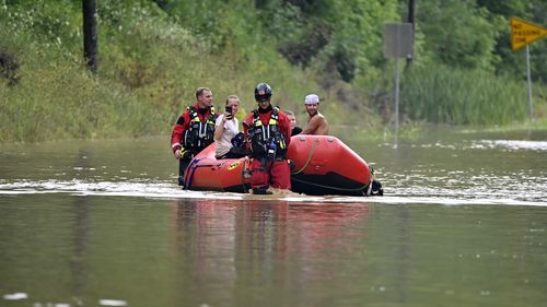 Members of the Winchester, Ky., Fire Department walk inflatable boats across flood waters over Ky. State Road 15 in Jackson, Ky., to pick up people stranded by the floodwaters Thursday, July 28, 2022. Flash flooding and mudslides were reported across the mountainous region of eastern Kentucky, where thunderstorms have dumped several inches of rain over the past few days. (AP Photo/Timothy D. Easley)