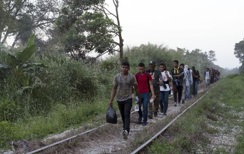 Migrantes caminan sobre las vías del tren mientras viajan desde Centroamérica hacia la frontera con Estados Unidos en Palenque, estado de Chiapas, México, el miércoles 10 de febrero de 2021. 