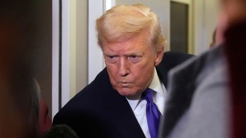 Başkan Donald Trump, Air Force One'da bir gazetecinin sorusunu dinliyor.