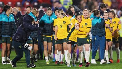 Hayley Raso celebrates with teammate Clare Polkinghorne as the Matildas walk off after their win over England.