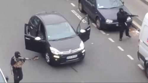 The two gunmen brandishing AK-47 assault rifles on the street outside the magazine offices. (Supplied)