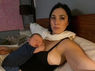 Singer Michelle Branch Lying in bed with her newborn lying on her chest taking a selfie from the side.