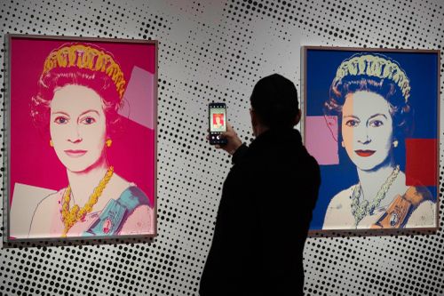 A man takes an image of a screen print depicting Queen Elizabeth II, one in a series of sixteen prints of four queens titled Reigning Queens, 1985, by Andy Warhol at museum Paleis Het Loo in Apeldoorn, Netherlands, Wednesday, Oct. 9, 2024, similar to a Warhol work stolen from a gallery in Oisterwijk, Netherlands, early Friday, Nov. 1, 2024.