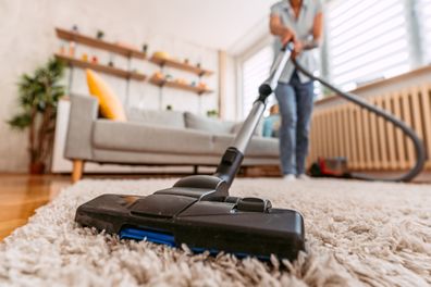 Woman vacuuming the carpet in her apartment.