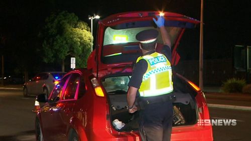 Police search the red Ford sedan, which had been reported stolen on December 18.