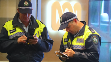 Two policemen stand in front of an ABC logo at the main entrance to the ABC building located at Ultimo in Sydney, Wednesday, June 5, 2019.