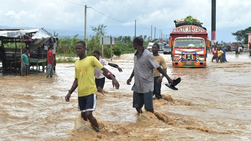 People try to cross the overflowing La Rouyonne river in the commune of Leogane, south of Port-au-Prince, Haiti, on October 5, 2016. 