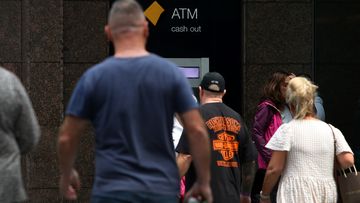 People move past a Commonwealth Bank ATM machine.