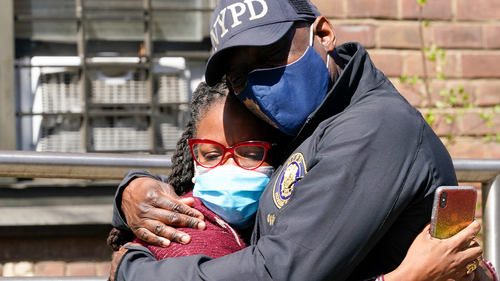 A police officer hugs a community leader outside the building where a man shot the mother of his child and two of her daughters dead before turning the gun on himself, Tuesday, April 6, 2021, in the Brownsville neighborhood of the Brooklyn borough of New York. 