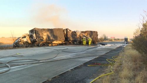 Firefighters continue to extinguish the truck fire resulting from the crash, which remains as a smouldering, charred structure on the Hume Highway near Albury (Supplied).