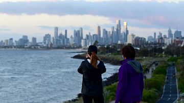 People watch the sunset over the city from Elwood Beach, Melbourne.
