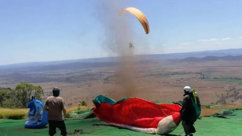 A man preparing to set off on a paragliding trip has received the fright of his life after a dust devil formed and swept him over a cliff.