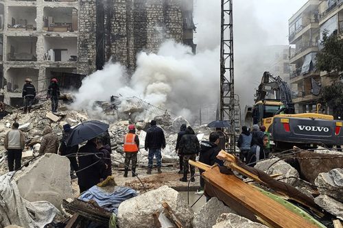 In this photo released by the Syrian official news agency SANA, civil defense workers and security forces search through the wreckage of collapsed buildings in Aleppo, Syria, Monday, Feb. 6, 2023. 