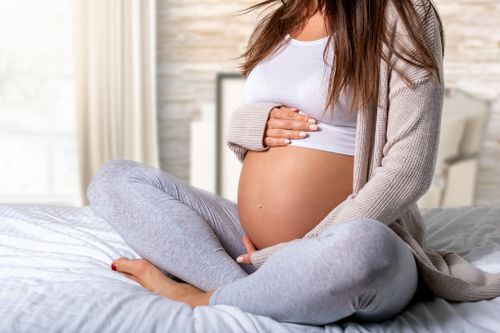 Pregnant woman sitting on bed