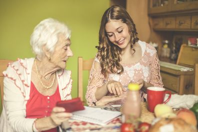 Senior woman at home with younger woman - money, spending, multi generations