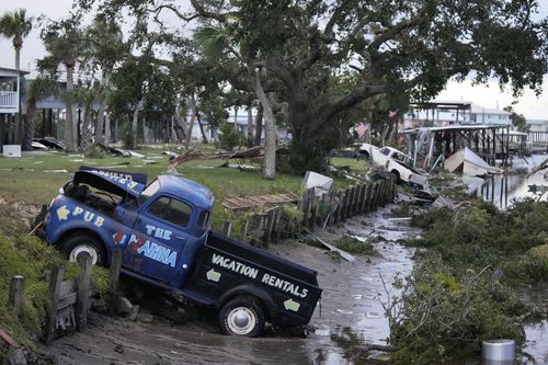 Pick up trucks and debris lie strewn in a canal in Horseshoe Beach, Fla., after the passage of Hurricane Idalia, Wednesday, Aug. 30, 2023. 
