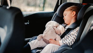 Cute girl napping with her toy in child safety seat in the car.