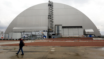 A man walks past a shelter covering the exploded reactor at the Chernobyl nuclear plant, in Chernobyl, Ukraine, Thursday, April 15, 2021. 