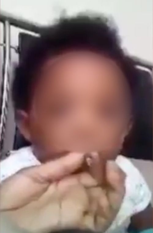 One of the videos showed the hand of an adult off-screen who appears to hold a small cigar to the child's lips. (Facebook)