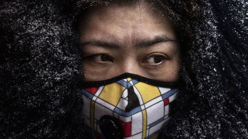 A Chinese woman wears a protective mask as she shops in a market on February 6, 2020 in Beijing, China.