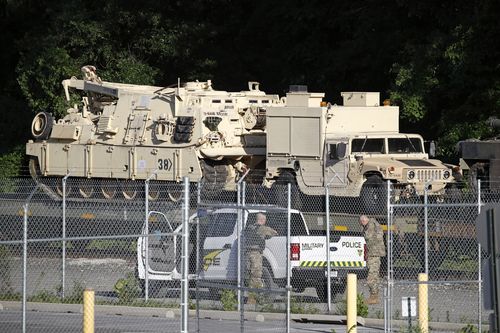 Military police stand military vehicles on a flat car in a rail yard, Monday, July 1, 2019, in Washington.