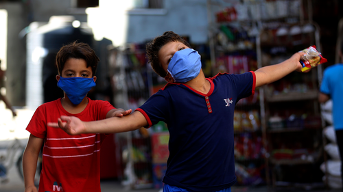 A child wearing a face mask reacts after shopping from a grocery store during a lockdown imposed during the coronavirus pandemic, at Shati refugee camp, in Gaza City, Thursday, Aug. 27, 2020.  (AP Photo/Adel Hana)