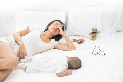 Woman lying on bed with newborn baby.