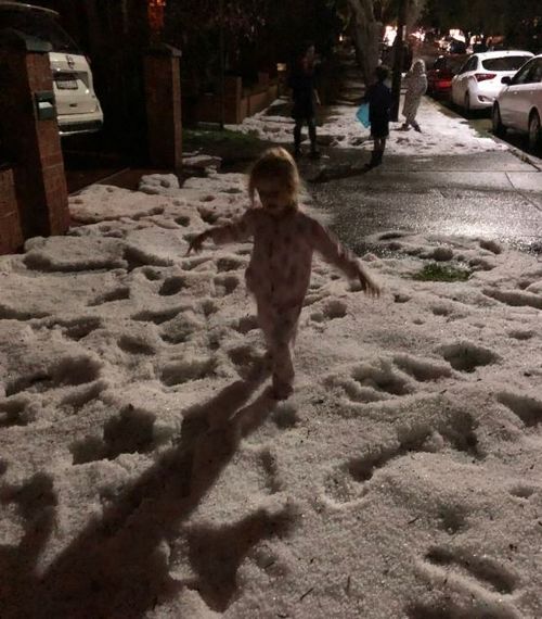 Kids play in the 'snow' as large hail blankets Sydney.