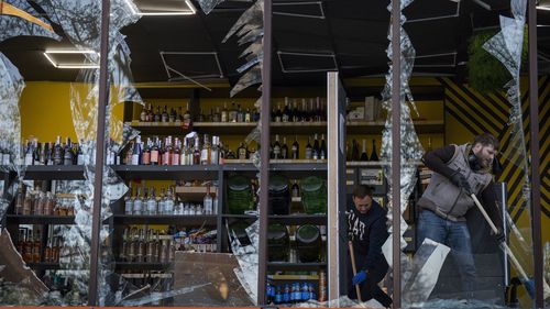 Employees at a liquor store clean the glasses broken during an explosion in Kyiv, Ukraine on Friday, April 29, 2022. Russia struck the Ukrainian capital of Kyiv shortly after a meeting between President Volodymyr Zelenskyy and U.N. Secretary-General António Guterres on Thursday evening. (AP Photo/Emilio Morenatti)