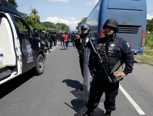 Mexican federal police stand guard along the road being used by a U.S.-bound, large caravan of Central American migrants.