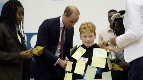Britain's Prince William sticks a post-it note on Daniel, aged 11 from Derbyshire, an anti-bullying ambassador.