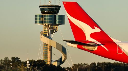 A Qantas Airbus A330-202 plane, registration VH-EBM, passing the air traffic control tower as she taxis at Sydney Kingsford-Smith Airport in preparation for departure as flight QF43 to Denpasar. 