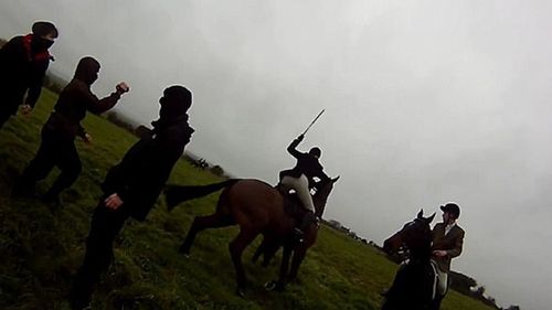 A huntswoman appears to hit a protester with her riding crop.