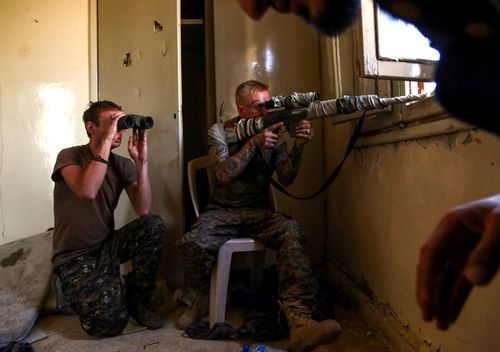 An American sniper (R) and British fighter supporting the Syriac Military Council in the fight against Islamic State guard a position in the suburb of al-Rumaniya on the western outskirts of Raqqa.