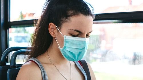 Young woman wearing face mask on public transport.