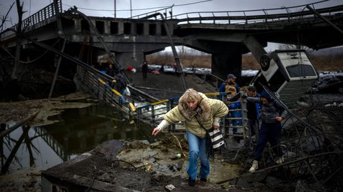 Woman runs as she flees with her family in Kyiv, Ukraine