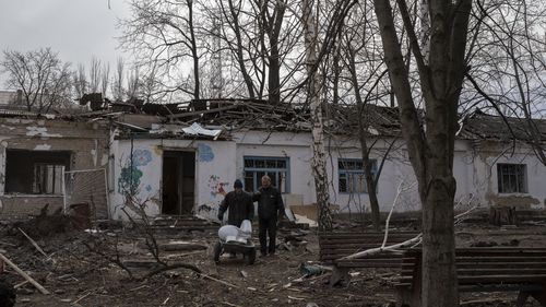 2022년 2월 25일 금요일 우크라이나 미콜라이프에서 한 남성이 러시아의 폭격으로 파괴된 정신병원 잔해에서 수거된 변기 카트를 옮기고 있다. (AP Photo/Petros Giannakouris)