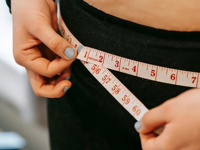 Stock image of a woman measuring her hips.