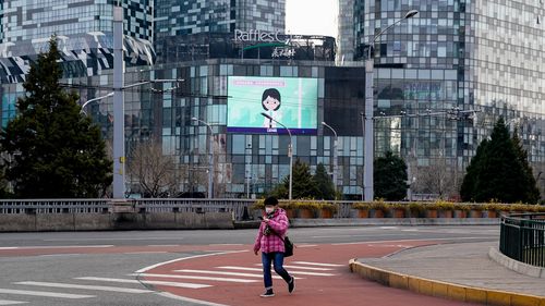 A Chinese woman wears a protective mask while walking in an empty street in Beijing, China. 