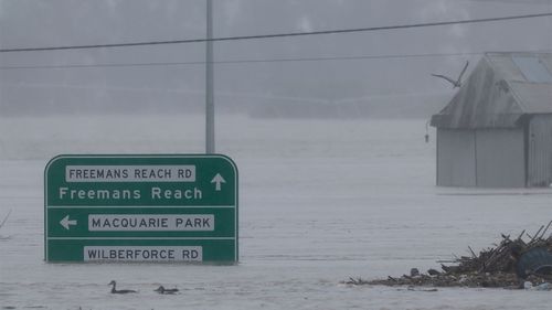Road signs are submerged under floodwater along the Hawkesbury River near the Windsor Bridge.