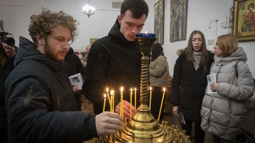 Люди зажигают свечи в память о британских добровольцах Крисе Бэрри и Эндрю Бэгшоу, погибших на опустошенной войной восточной Украине, во время поминовения в столовой возле Софийского собора в Киеве, Украина.