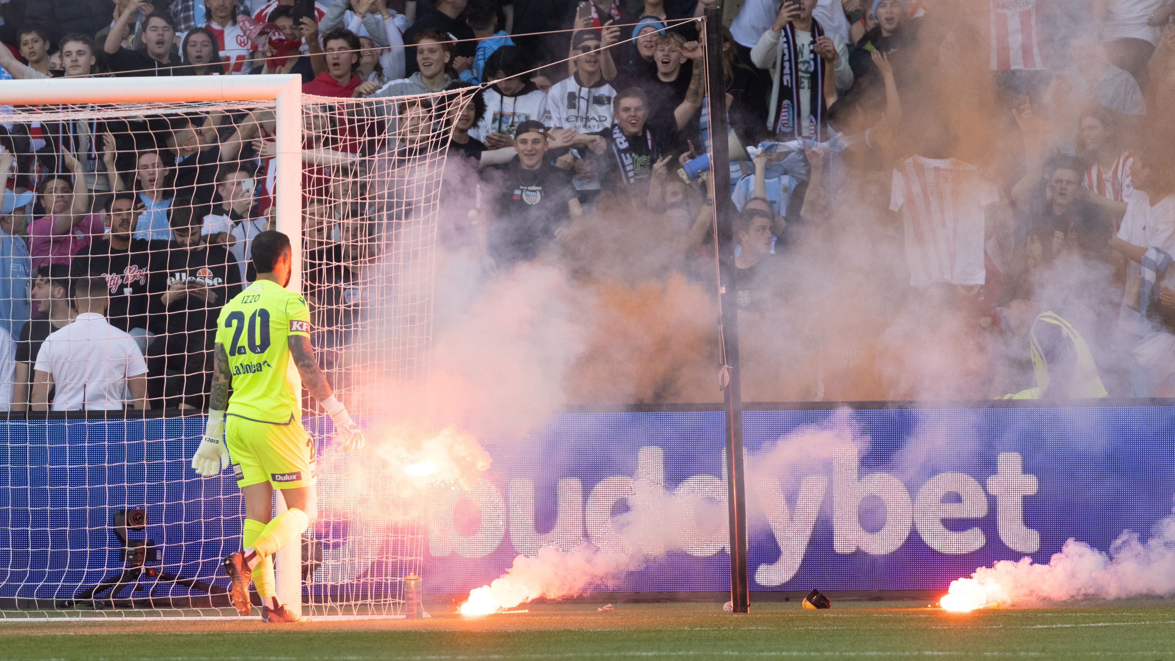 Victory goalkeeper Paul Izzo picks up flares during an A-League Men&#x27;s match between Melbourne City and Melbourne Victory.