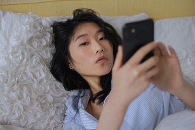 Dating app, digital dating, woman using her phone in bed