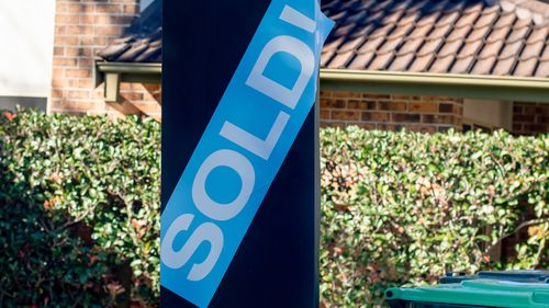 Placa de venda perto de prédio residencial com um adesivo vendido 