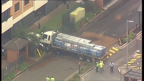 An aerial view of the truck which pinned a car close to the wall of a unit block.