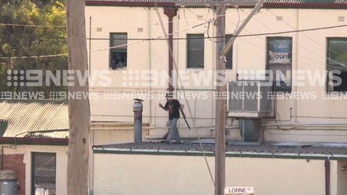 The man, who is armed with what apepars to be a machete, is refusing to come down from the roof of the local pub. (9NEWS)