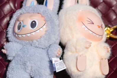 A guest wears a burgundy bordeaux woven Bottega Veneta Andiamo leather bag, light blue Labubu bag charm, cream Labubu bag charm, outside Elie Saab, during the Paris Fashion week Women's Fall/Winter 2025-2026 on March 8, 2025 in Paris, France. 